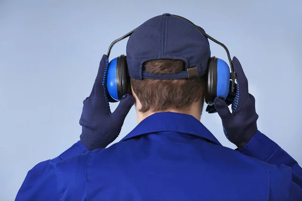 Male worker with headphones on grey background. Hearing protection equipment — Stock Photo, Image