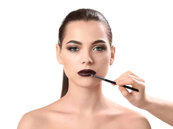 Professionel visage kunstner anvender makeup på kvindens ansigt på hvid baggrund - Stock-foto