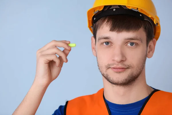 Trabajador masculino con tapón auricular sobre fondo gris. Equipo de protección auditiva — Foto de Stock