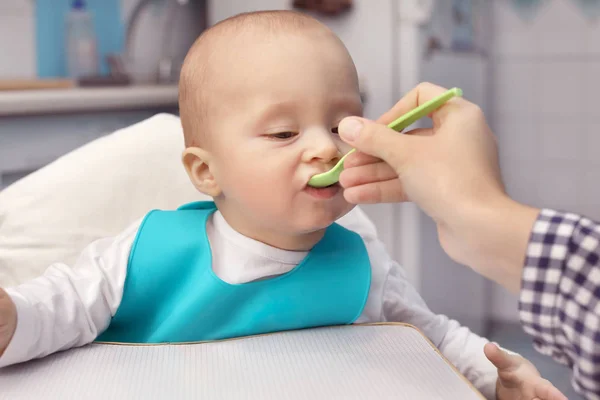 Madre alimentando al bebé con cuchara en el interior — Foto de Stock