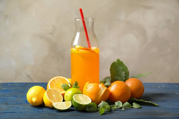 Bottle of tasty lemonade and citrus fruits on table — Stock Photo, Image