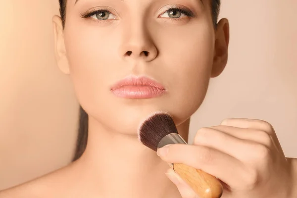 Professionell visage konstnären tillämpa makeup på kvinnans ansikte mot ljus bakgrund — Stockfoto