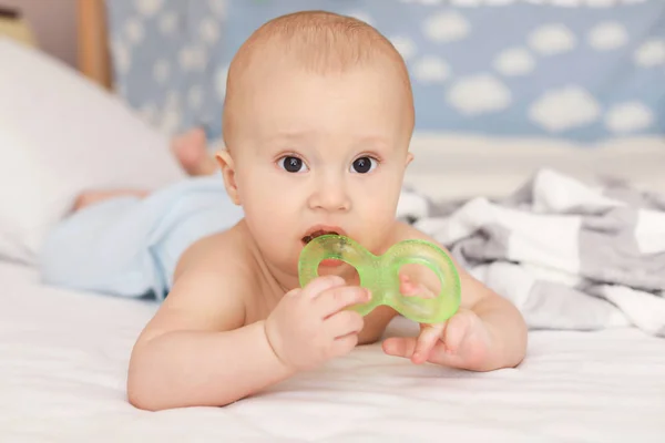 Bebê bonito com brinquedo de dentição deitado na cama em casa — Fotografia de Stock