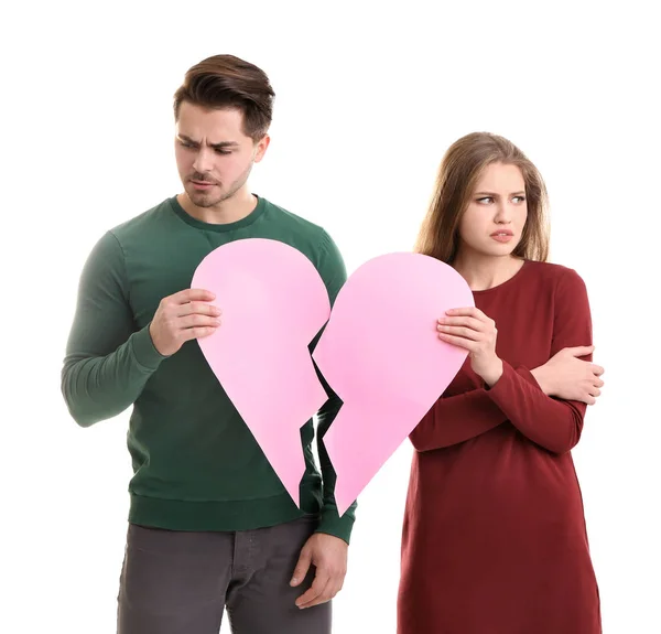 Young couple holding halves of broken heart on white background. Relationship problems — Stock Photo, Image