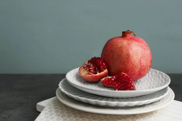 Tellerstapel und Granatapfel auf dem Tisch — Stockfoto