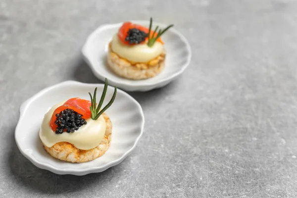 Tasty appetizer with black caviar and salmon on plates — Stock Photo, Image