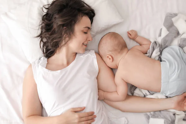 Joven madre y su bebé tumbados en la cama en casa — Foto de Stock