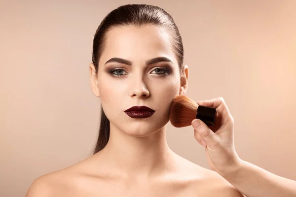 Professionele visage kunstenaar toepassing van make-up op het gezicht van de vrouw tegen de lichte achtergrond — Stockfoto