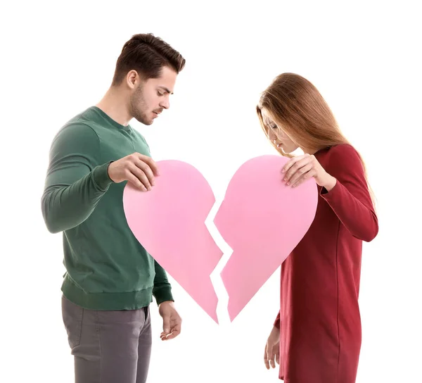 Pareja joven sosteniendo mitades de corazón roto sobre fondo blanco. Problemas de relación — Foto de Stock