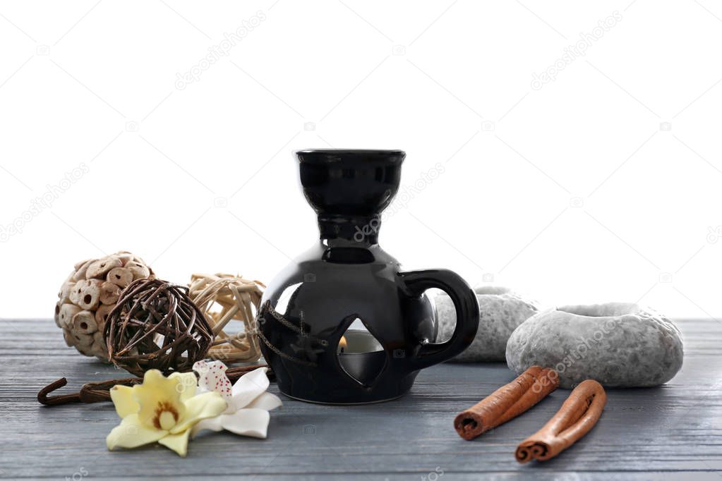 Aroma lamp and decor on table against white background