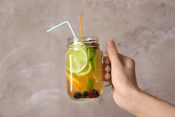 Mulher segurando frasco de pedreiro com limonada saborosa no fundo claro — Fotografia de Stock