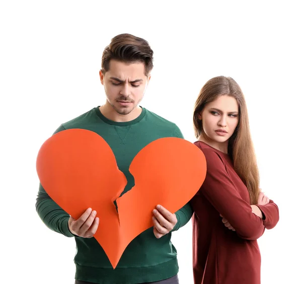 Joven hombre rasgando corazón de papel cerca de su novia en el fondo blanco. Problemas de relación — Foto de Stock