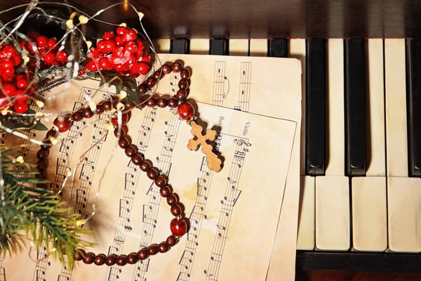 Weihnachtskomposition mit Rosenkranzperlen und Notenblättern auf dem Klavier — Stockfoto