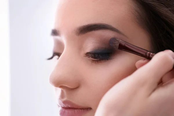 Professionell makeupartist arbetar med kvinna, inomhus — Stockfoto