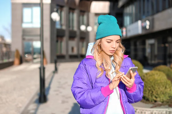 Ung kvinna i snygg outfit med mobiltelefon utomhus — Stockfoto