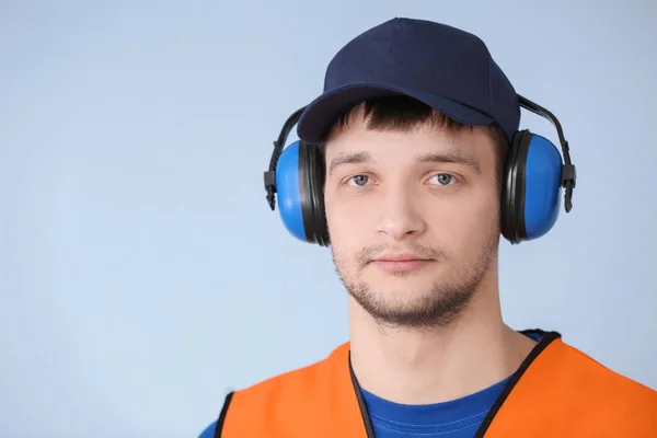 Manliga arbetare med hörlurar på grå bakgrund. Förhandlingen skyddsutrustning — Stockfoto