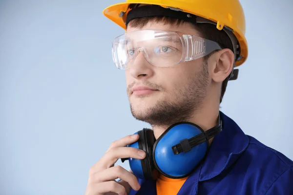 Männlicher Arbeiter mit Kopfhörern auf grauem Hintergrund. Gehörschutzausrüstung — Stockfoto