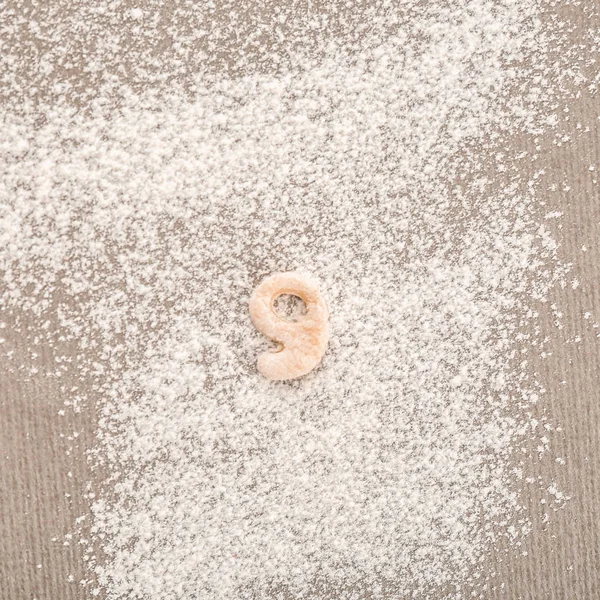 Figura Nueve hecha de masa cruda sobre harina — Foto de Stock