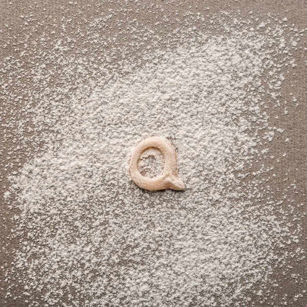 Lettera Q fatta di pasta cruda sulla farina — Foto Stock