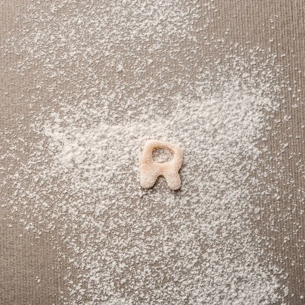 Letter R made of raw dough on flour — Stock Photo, Image