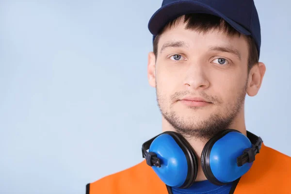 Άνδρας εργαζόμενος με ακουστικά σε γκρι φόντο. Εξοπλισμός προστασίας της ακοής — Φωτογραφία Αρχείου