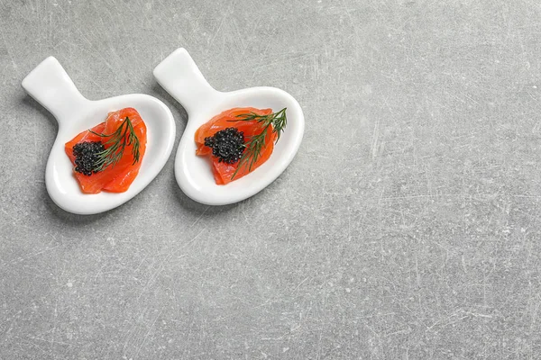 Sabrosos aperitivos con caviar negro y salmón sobre fondo gris —  Fotos de Stock