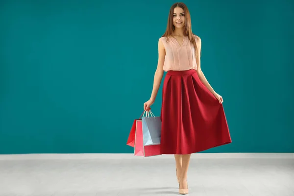 Junge Frau mit Einkaufstasche gegen Farbwand — Stockfoto