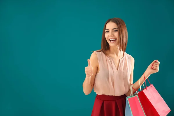 Mujer joven con bolsas de compras en el fondo de color —  Fotos de Stock