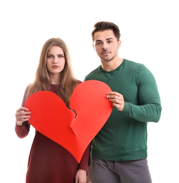 Casal jovem segurando coração partido no fundo branco. Problemas de relacionamento — Fotografia de Stock