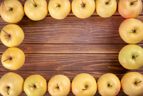Marco hecho de sabrosas manzanas amarillas maduras sobre fondo de madera —  Fotos de Stock