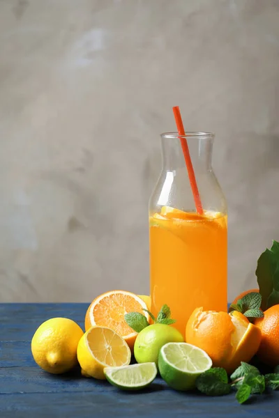 Bottle of tasty lemonade and citrus fruits on table — Stock Photo, Image