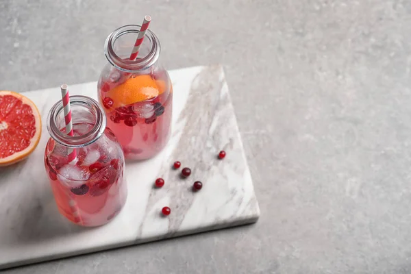 Sabrosa limonada con pomelo y bayas en botellas en la mesa — Foto de Stock