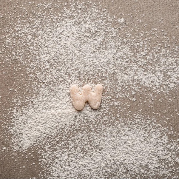 Letter W made of raw dough on flour — Stock Photo, Image