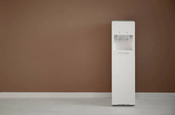 Modern water cooler near color wall