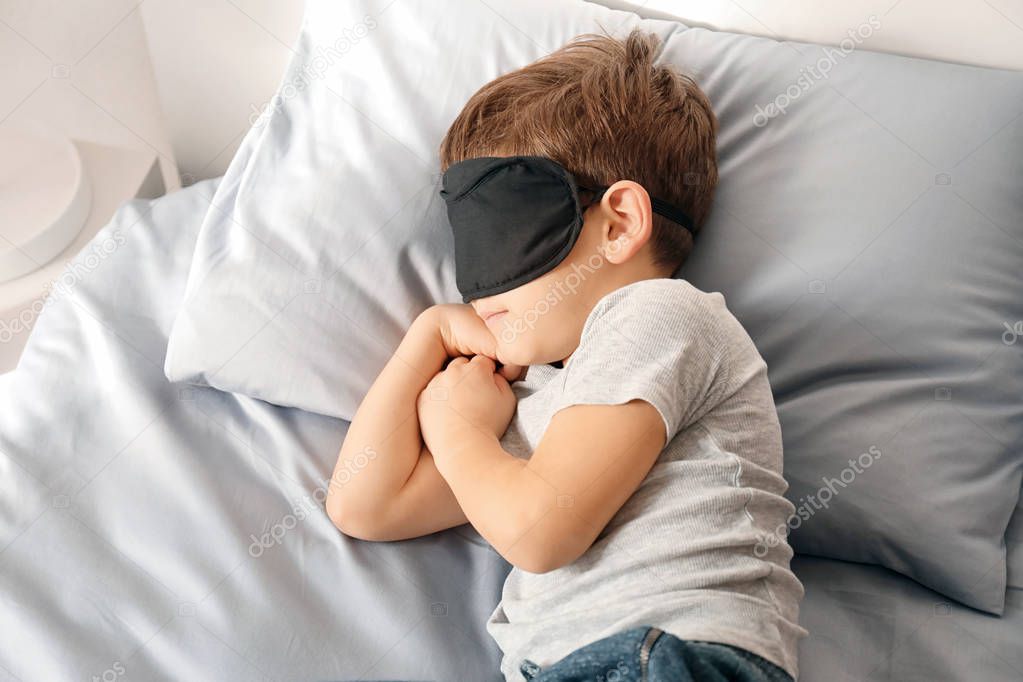 Cute little boy with mask sleeping in bed