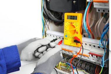 Young electrician measuring voltage in distribution board, closeup clipart