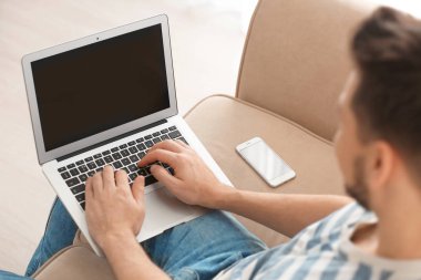 Bilgisayarlı genç adam evde çalışıyor.