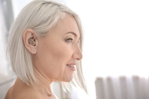 Rijpe vrouw met gehoorapparaat binnenshuis — Stockfoto