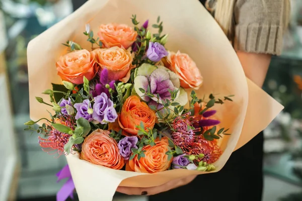 Female florist holding beautiful bouquet in flower shop