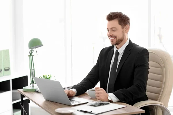 Бизнесмен с ноутбуком работает в офисе — стоковое фото