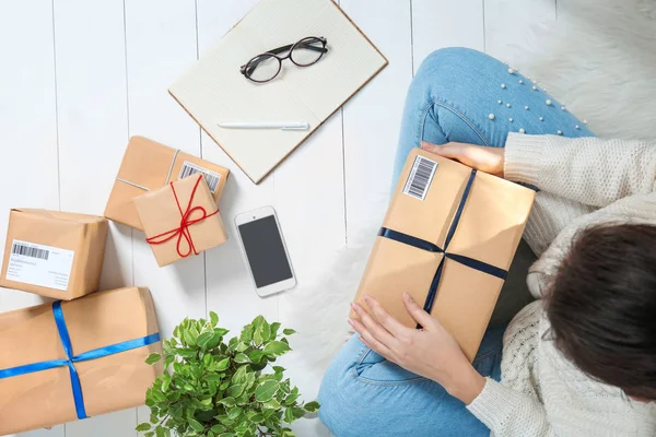 Startupper fêmea preparando pacotes para envio para clientes dentro de casa — Fotografia de Stock