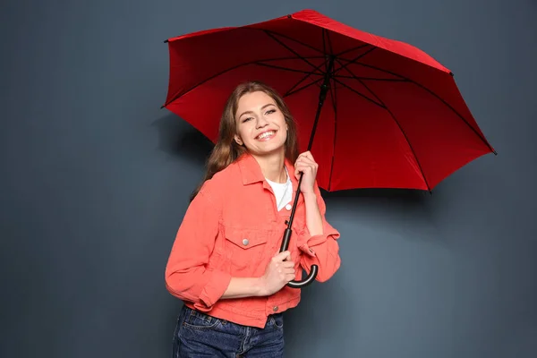 Jonge vrouw met rode paraplu op kleur achtergrond — Stockfoto