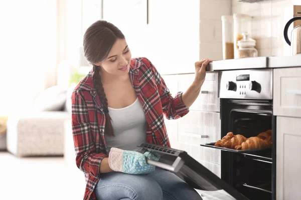 Kvinna som baka croissanter i ugn inomhus — Stockfoto