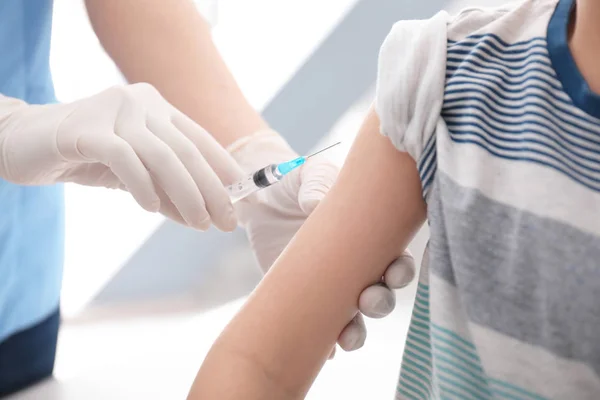 Médico vacunando a un niño pequeño en la clínica, primer plano — Foto de Stock