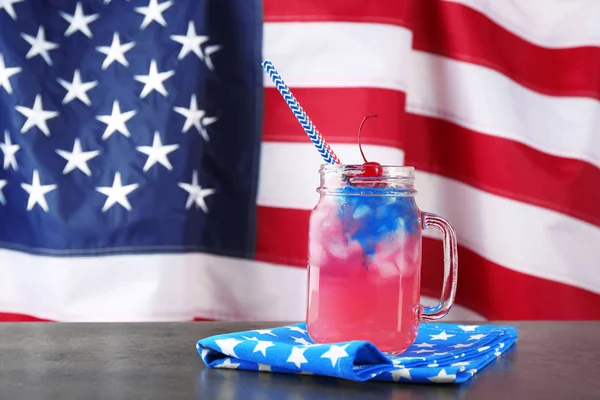 Glas mit Alkoholcocktail auf Tisch gegen amerikanische Flagge — Stockfoto