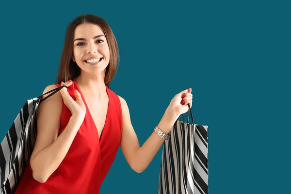 Mujer joven con bolsas de compras en el fondo de color —  Fotos de Stock