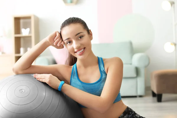 Beautiful sporty woman resting after training with fitball at home