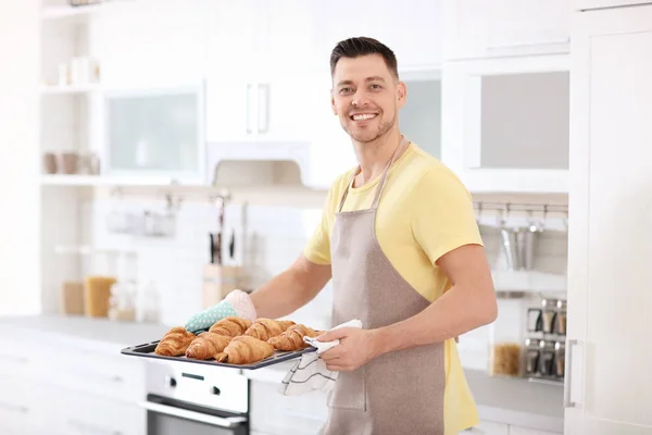 Man håller bakplåt med läckra hembakade croissanter i köket — Stockfoto