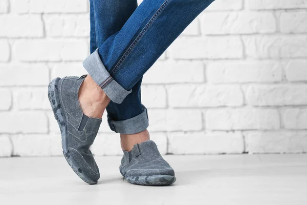 Man in casual shoes near brick wall