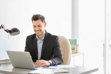 Ofiste çalışan dizüstü bilgisayar ile yakışıklı işadamı